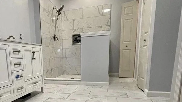 A walk-in shower in a white-toned bathroom