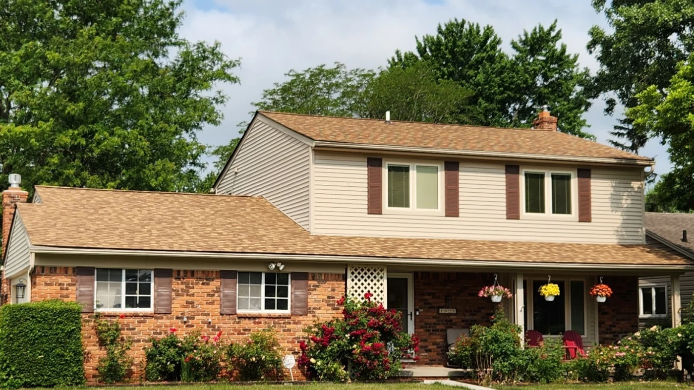 A brown shingle roof on a tan home recently installed by Kroll Construction