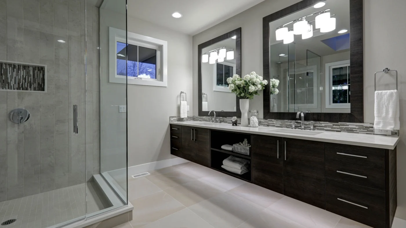 A bathroom with a walk-in shower and a long, dark wood vanity