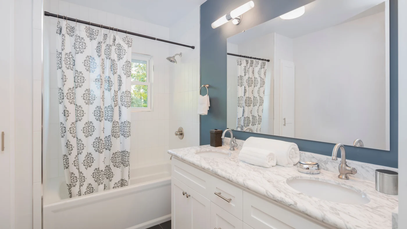 Spacious bathroom with white countertops and dark gray-blue accent wall