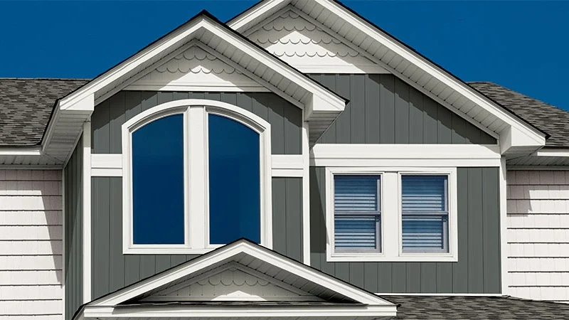 Closeup of the upper floor windows of a home with green Alside siding