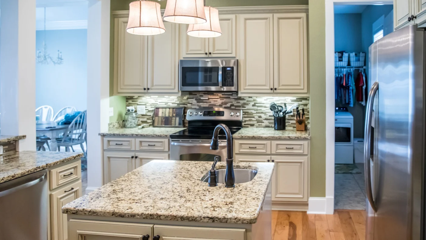 A stylish kitchen with an island, stainless steel appliances, and beige cabinets