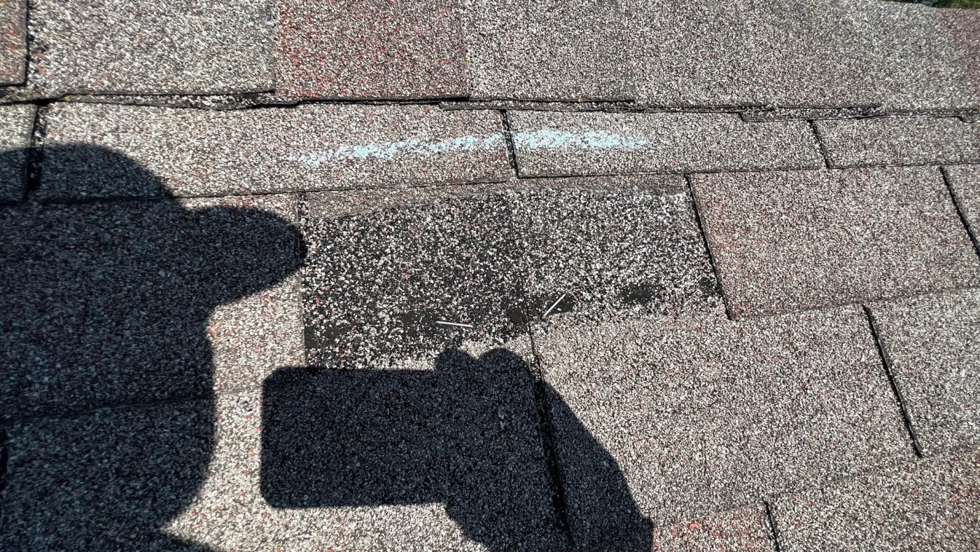 Kroll Construction taking a photo of missing shingles on a roof due to storm damage