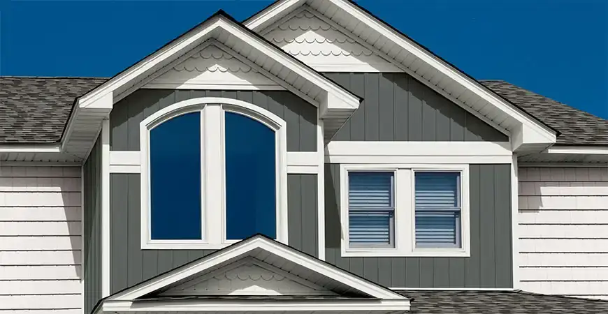 Closeup of upper floor of home with new windows and dark gray vertical siding