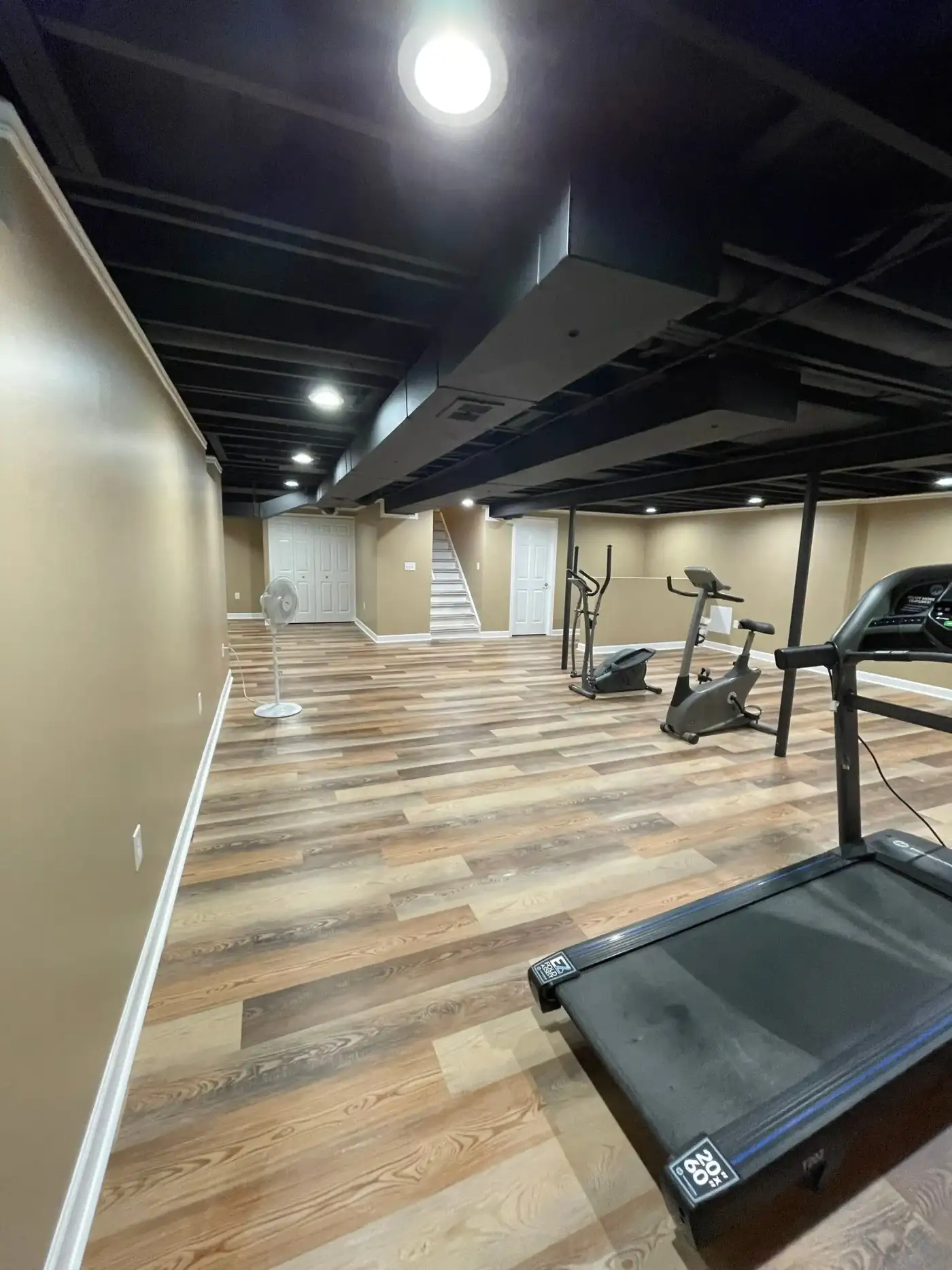 Basement remodeled into home gym with wood flooring
