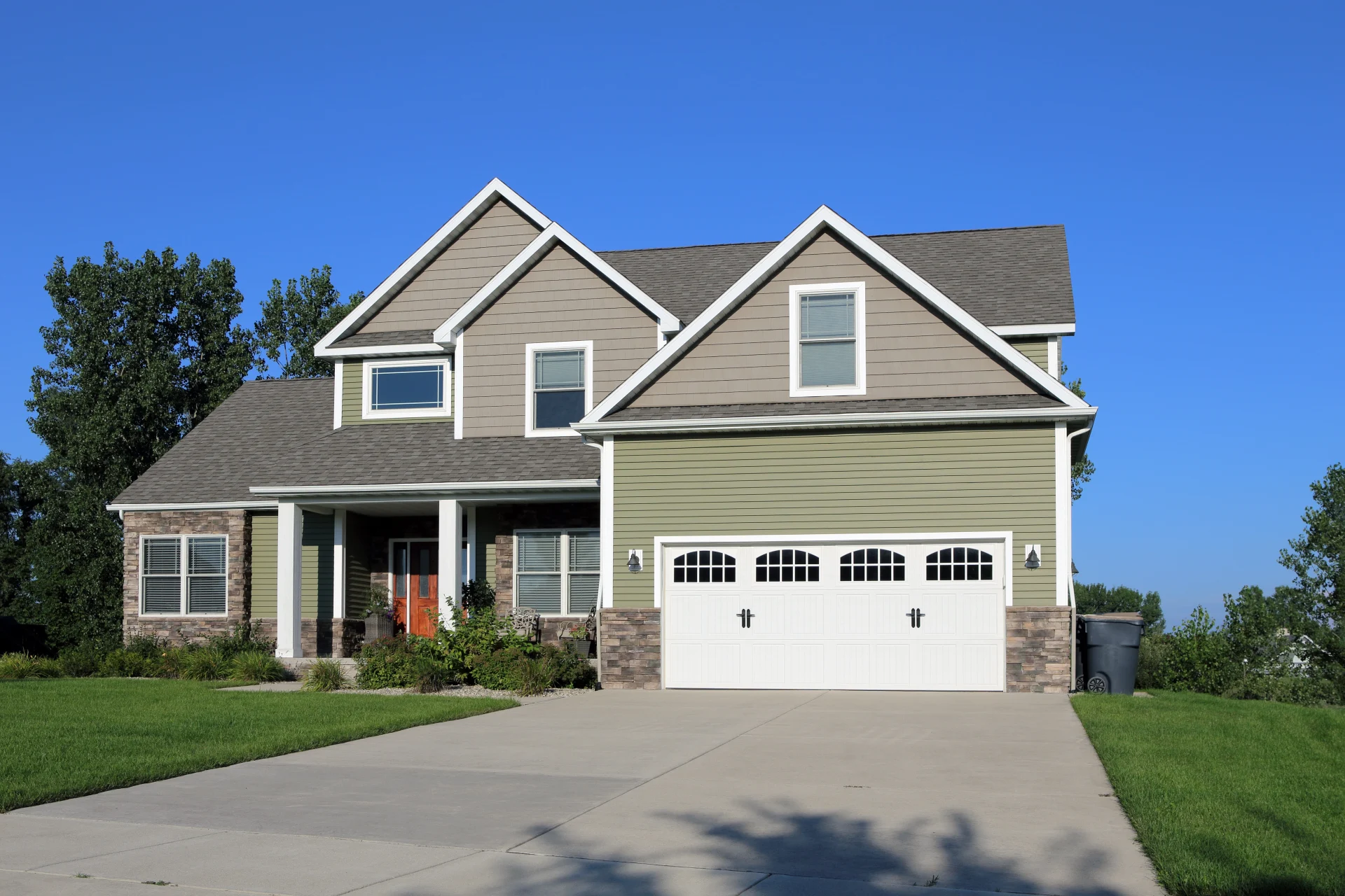 Stunning green siding on the front of a large suburban house