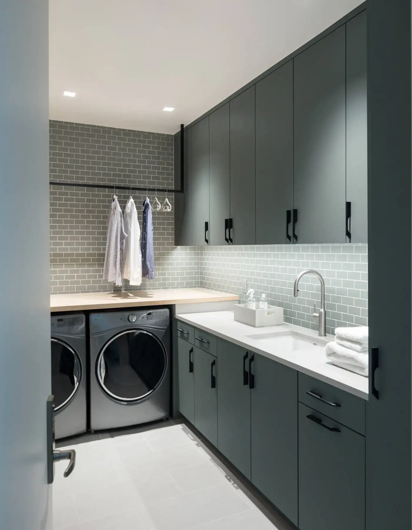 Laundry room with dark green cabinets