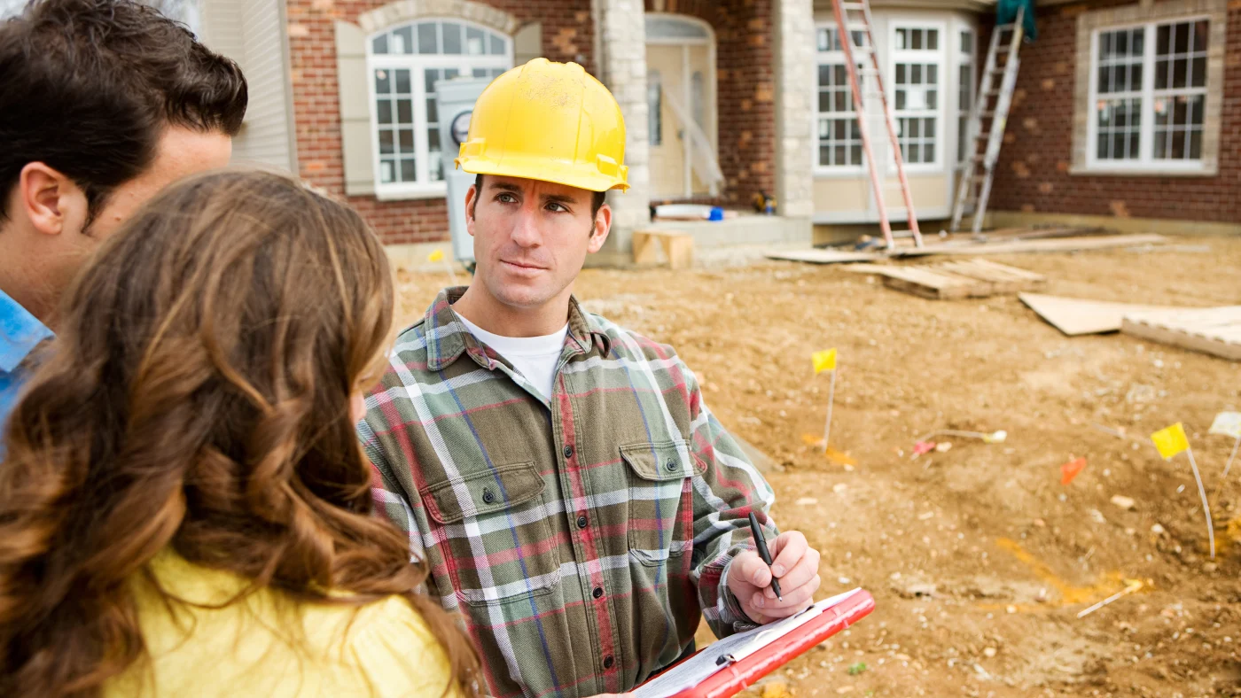 A contractor speaks to homeowners in front of their house