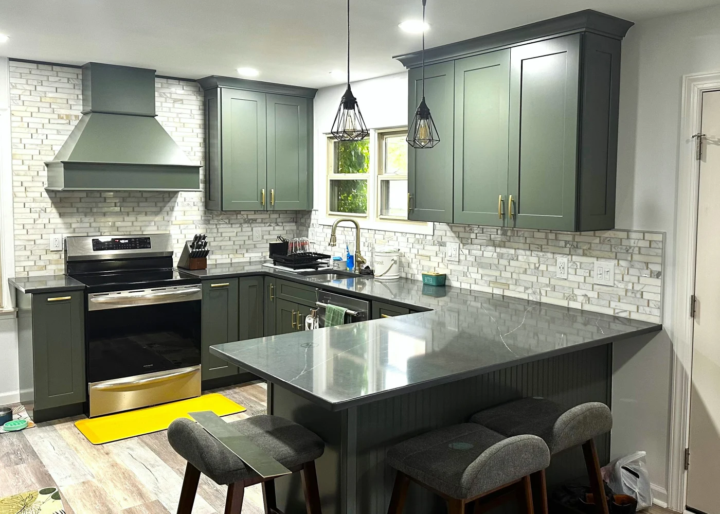 Image of a newly renovated kitchen with green cabinetry and gold accents