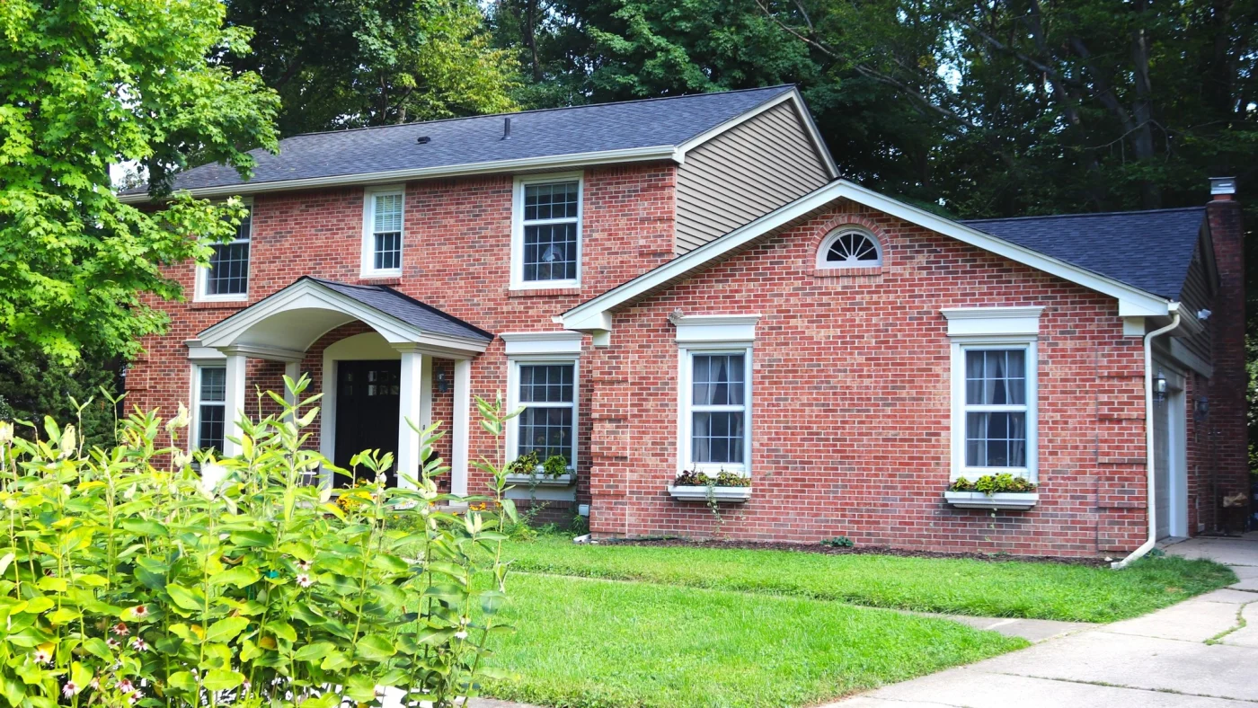 Gorgeous red brick home with white trimmed windows, grey asphalt roof, and black front door