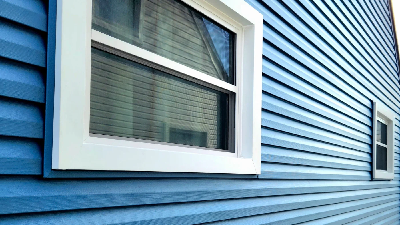 Side view of home with royal blue vinyl siding and white-framed replacement windows