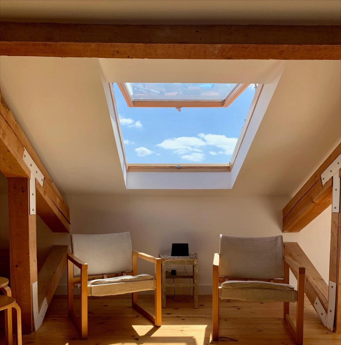 Image of a small attic roof with two chairs and an open skylight
