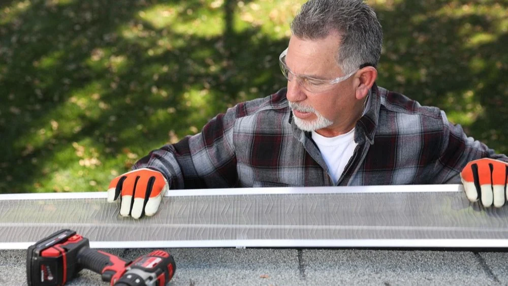 Man with safety glasses and gloves installing new gutter guards on gutters