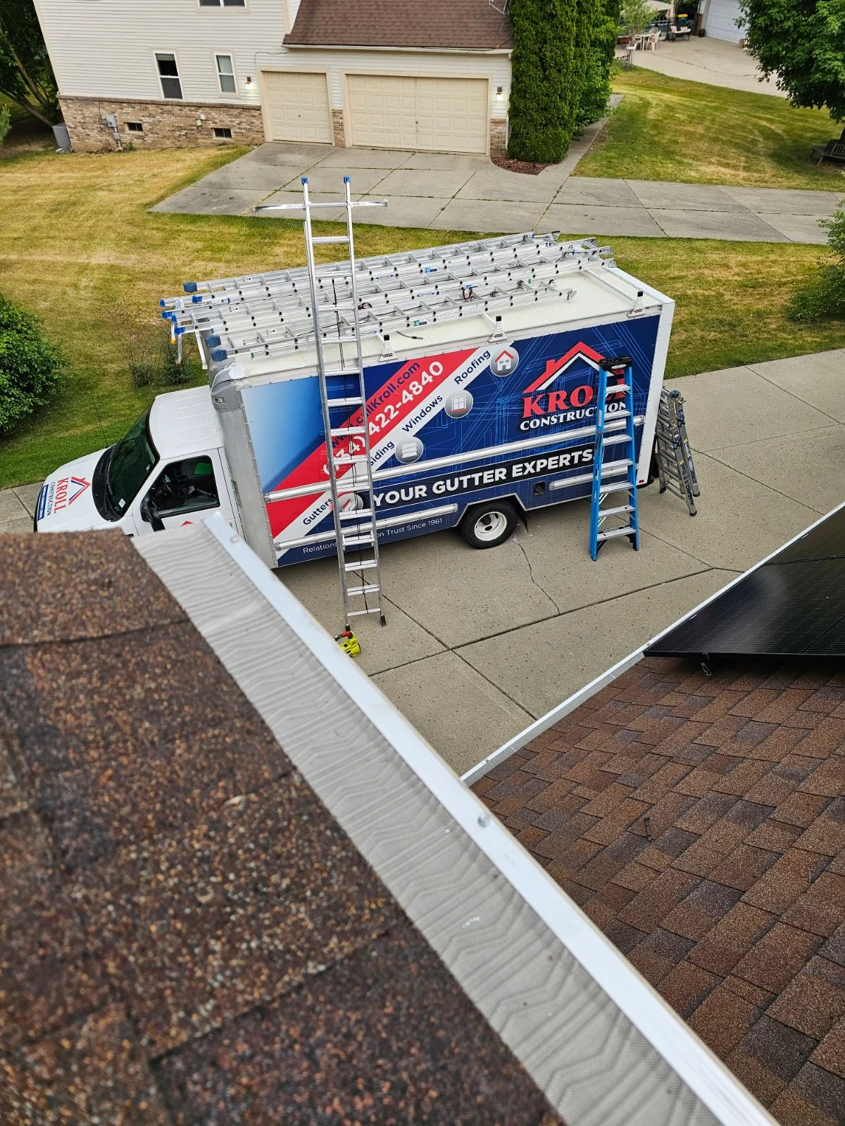 Angled view of gutter guards on seamless gutters, with Kroll Construction truck in the background
