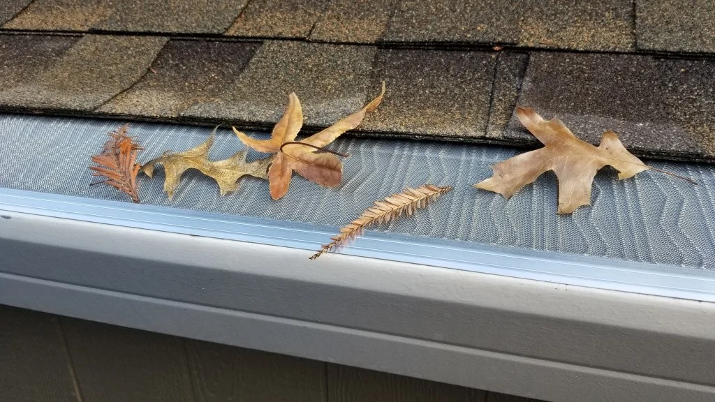Close-up picture of newly installed mesh gutter guards with a couple of fall leaves on them.
