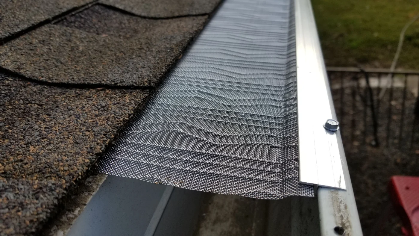 Gutter guard on the gutters of a house with an asphalt shingle roof.