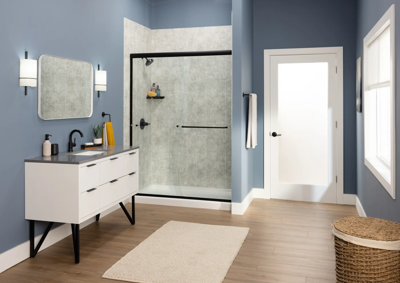 A bathroom with blue walls and a walk-in shower with gray surrounds