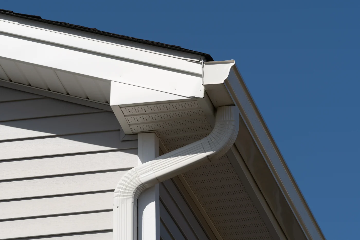 A white seamless gutter system installed on a home with vinyl siding.