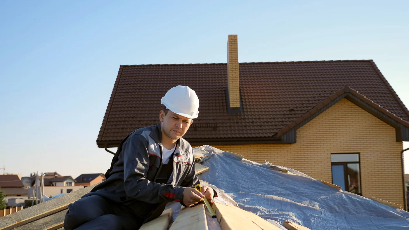 A roofer making repairs to a roof after extensive storm damage.