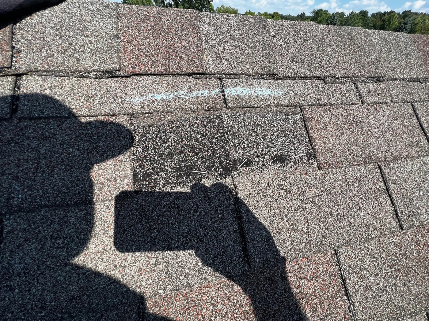 A close-up view of a damaged shingle after storm damage.