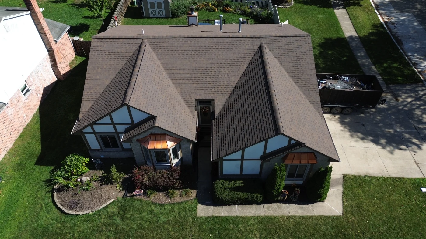 An aerial view of a white house with a brown asphalt shingle roof.
