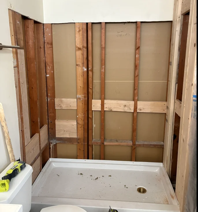 The shower space down to the studs with a new base being installed before the shower walls.